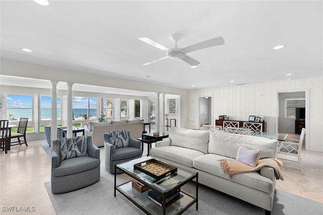 living room with ornate columns, a water view, and ceiling fan