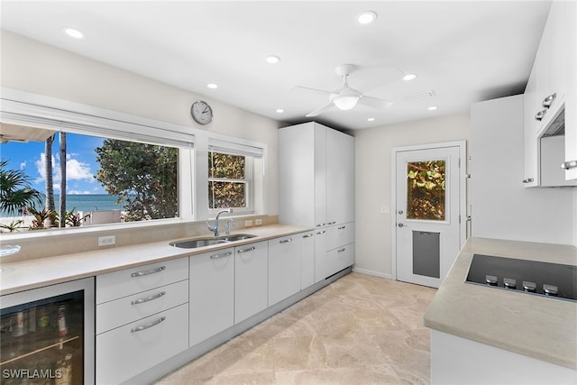 kitchen with white cabinets, sink, beverage cooler, and ceiling fan