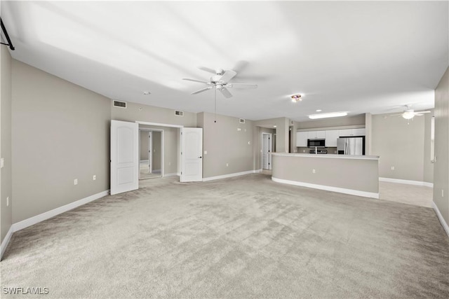 unfurnished living room with light colored carpet and ceiling fan