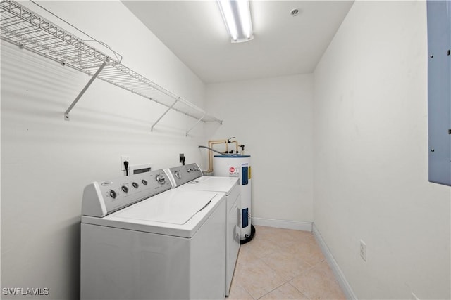 clothes washing area featuring light tile patterned flooring, washing machine and dryer, and water heater