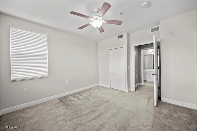 unfurnished bedroom with a closet, light colored carpet, and ceiling fan