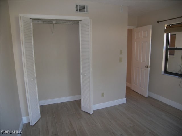 unfurnished bedroom with light hardwood / wood-style flooring and a closet