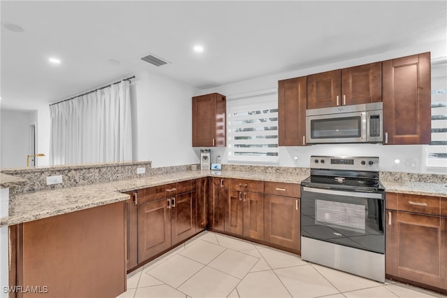 kitchen with kitchen peninsula, appliances with stainless steel finishes, and light stone counters