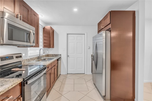 kitchen featuring light stone counters, sink, light tile patterned floors, and appliances with stainless steel finishes