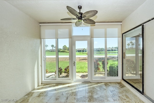 unfurnished sunroom featuring ceiling fan