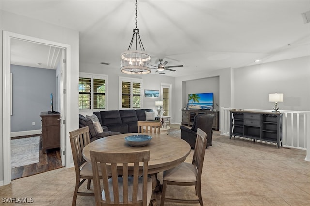 tiled dining room with ceiling fan with notable chandelier