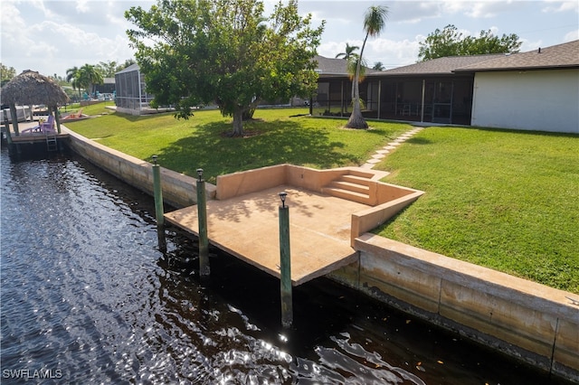 view of yard with a lanai, a water view, and a boat dock