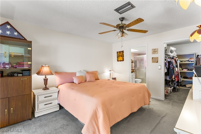 bedroom with a closet, a spacious closet, connected bathroom, light carpet, and ceiling fan