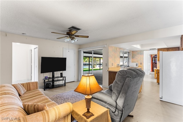 living room featuring a textured ceiling and ceiling fan