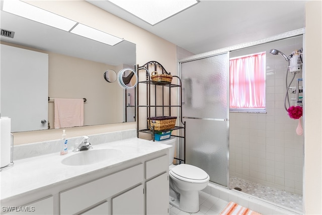 bathroom featuring toilet, vanity, tile patterned flooring, and a shower with shower door