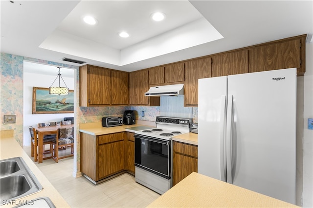 kitchen with tasteful backsplash, white appliances, decorative light fixtures, and a raised ceiling