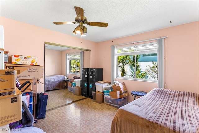 bedroom with a textured ceiling, multiple windows, ceiling fan, and a closet