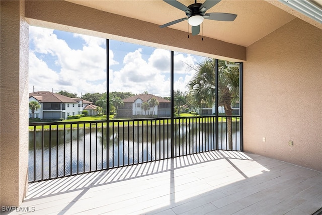 unfurnished sunroom with ceiling fan, a healthy amount of sunlight, and a water view