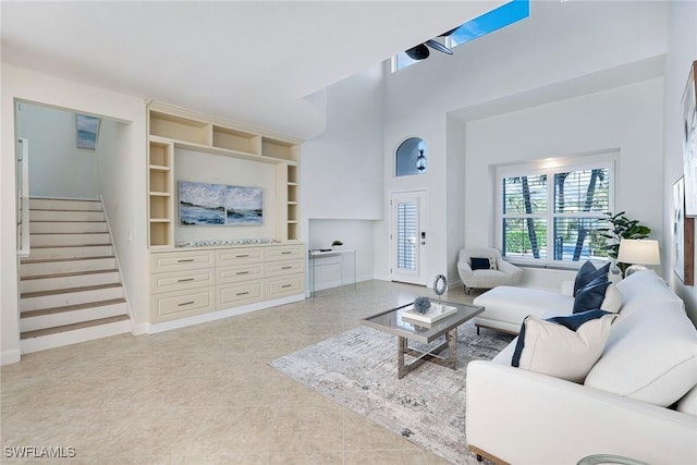 living room with a towering ceiling and built in shelves