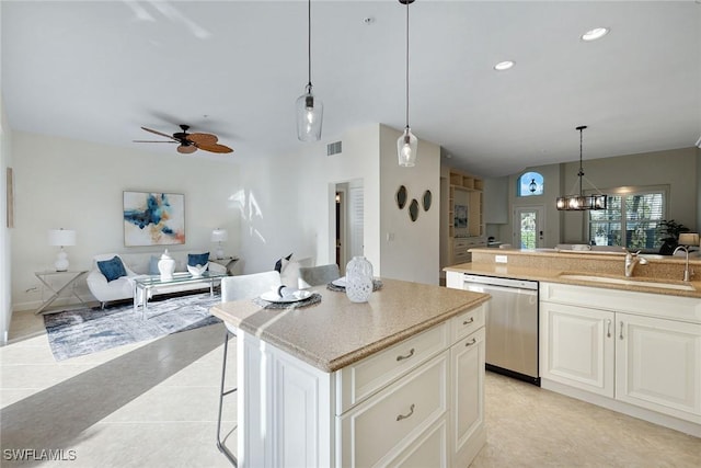 kitchen featuring pendant lighting, sink, a breakfast bar, a center island, and stainless steel dishwasher