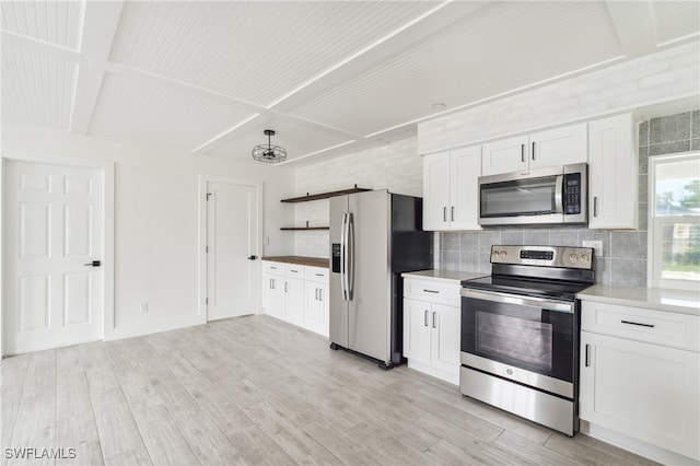 kitchen with white cabinets, stainless steel appliances, backsplash, and light hardwood / wood-style flooring