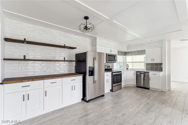 kitchen with white cabinetry, appliances with stainless steel finishes, wooden counters, light wood-type flooring, and pendant lighting