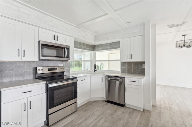 kitchen featuring white cabinetry, stainless steel appliances, light hardwood / wood-style floors, and backsplash