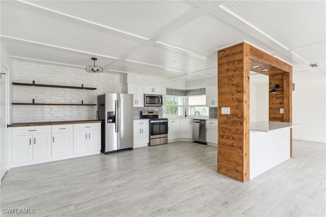 kitchen with white cabinets, hanging light fixtures, light hardwood / wood-style floors, and stainless steel appliances