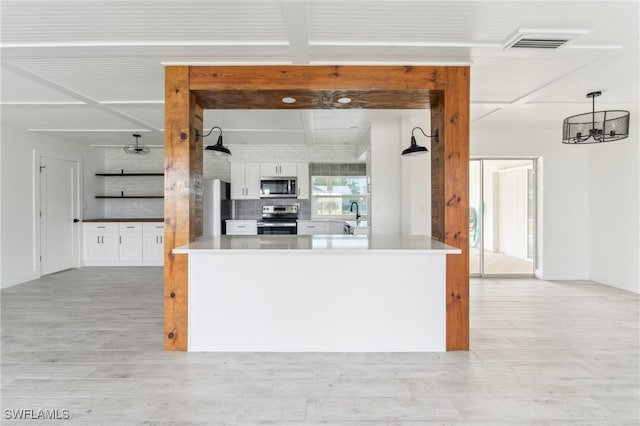 kitchen with light hardwood / wood-style flooring, pendant lighting, appliances with stainless steel finishes, and white cabinets