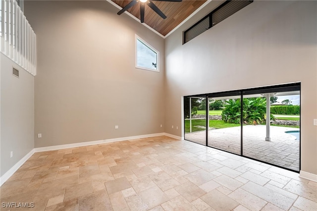 empty room featuring a high ceiling, wooden ceiling, and ceiling fan