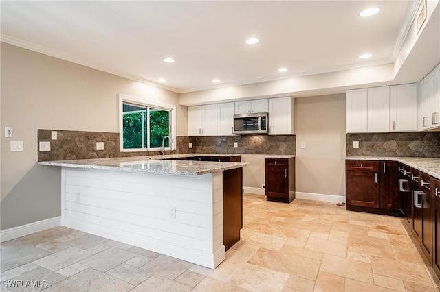 kitchen featuring dark brown cabinets, kitchen peninsula, tasteful backsplash, and light stone countertops