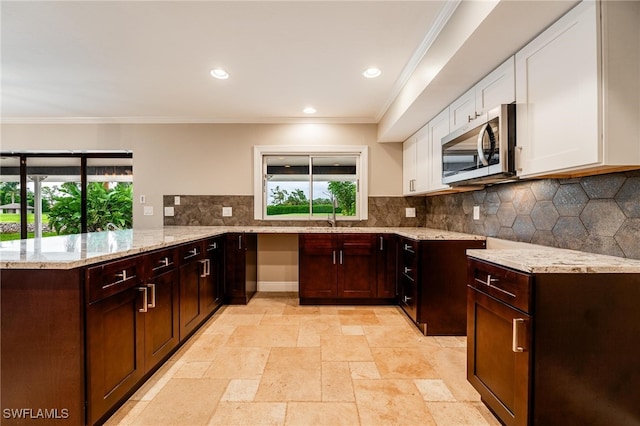 kitchen with white cabinetry, kitchen peninsula, a healthy amount of sunlight, and backsplash