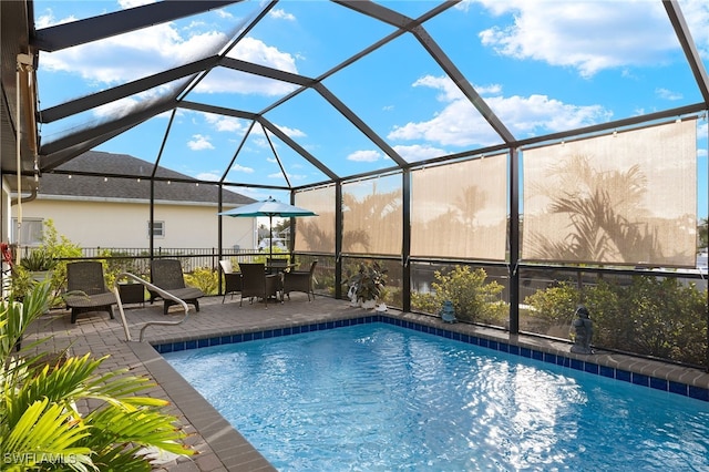 view of pool with glass enclosure and a patio