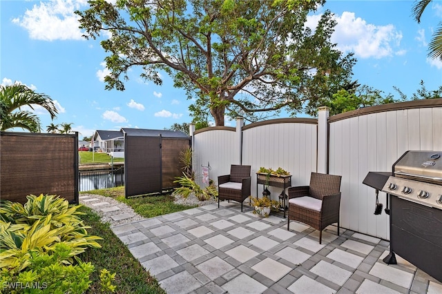 view of patio with a storage unit, area for grilling, and a water view