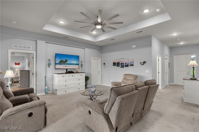 carpeted living room with ceiling fan and a raised ceiling