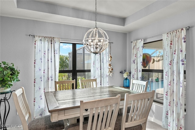 dining space with a wealth of natural light, carpet floors, a chandelier, and a tray ceiling