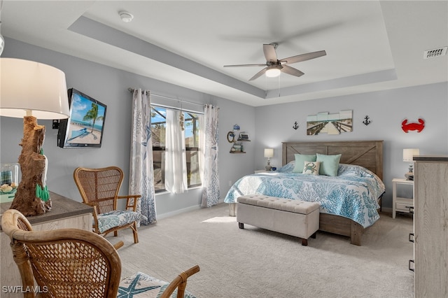 carpeted bedroom featuring ceiling fan and a tray ceiling