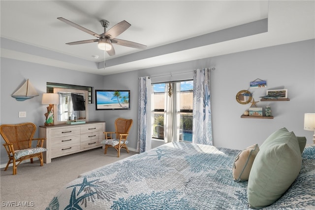 carpeted bedroom with ceiling fan and a raised ceiling