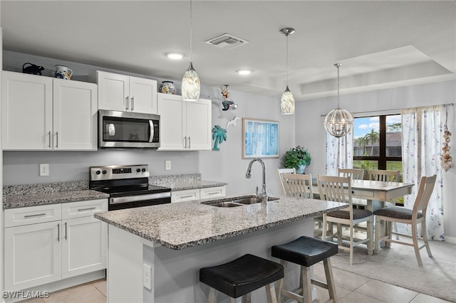 kitchen featuring white cabinets, a center island with sink, appliances with stainless steel finishes, and sink