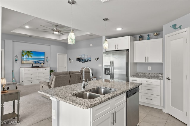 kitchen with stainless steel appliances, white cabinets, light carpet, sink, and a tray ceiling