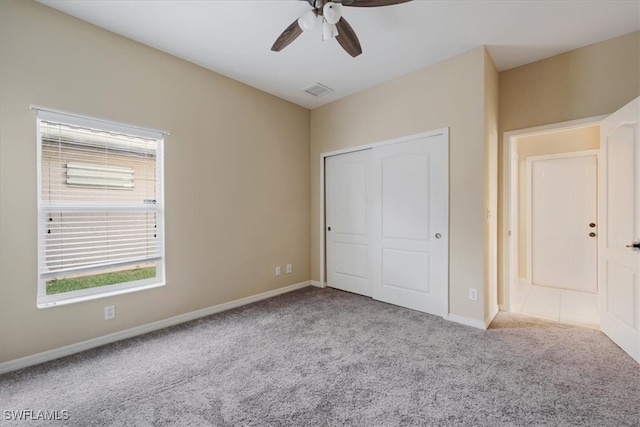 unfurnished bedroom with ceiling fan, light colored carpet, and a closet