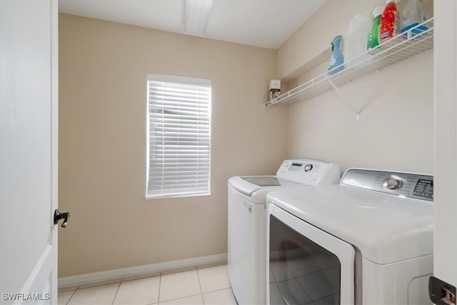 clothes washing area with washing machine and dryer and light tile patterned floors