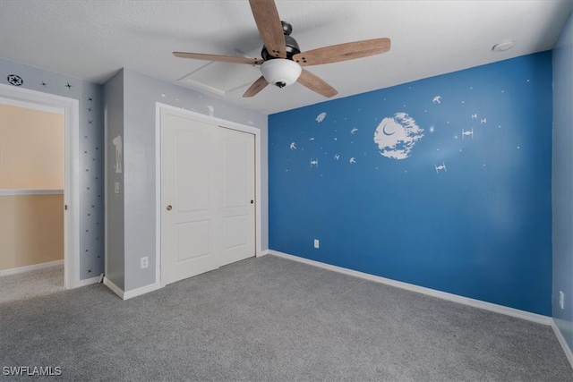 unfurnished bedroom with a textured ceiling, carpet, ceiling fan, and a closet