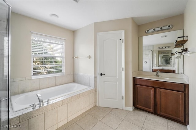 bathroom featuring vanity, tile patterned floors, and a relaxing tiled tub