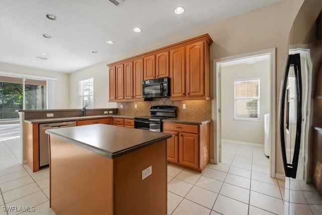 kitchen with black appliances, tasteful backsplash, a kitchen island, and sink