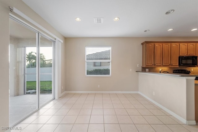 kitchen with black appliances, kitchen peninsula, and light tile patterned floors