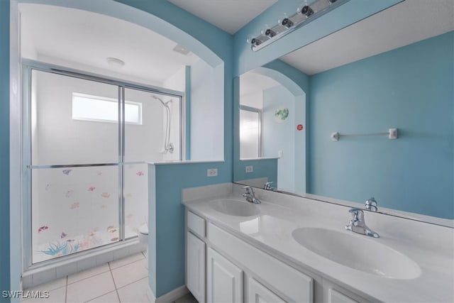 bathroom featuring tile patterned flooring, vanity, toilet, and a shower with door