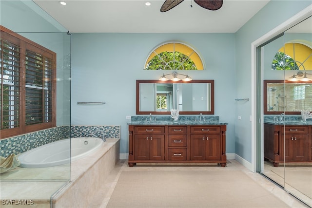 bathroom with ceiling fan, a healthy amount of sunlight, vanity, and tiled tub