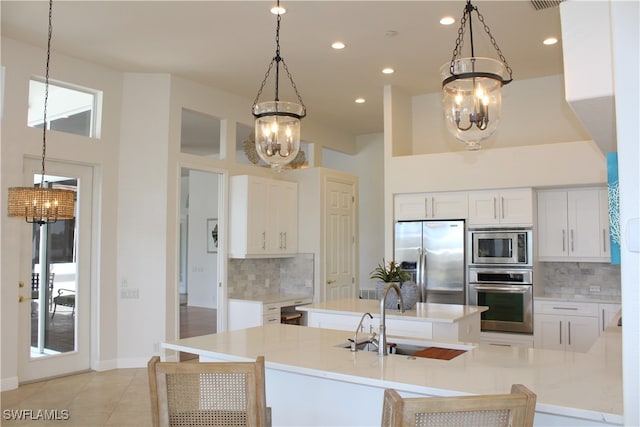 kitchen with tasteful backsplash, stainless steel appliances, sink, an inviting chandelier, and white cabinetry