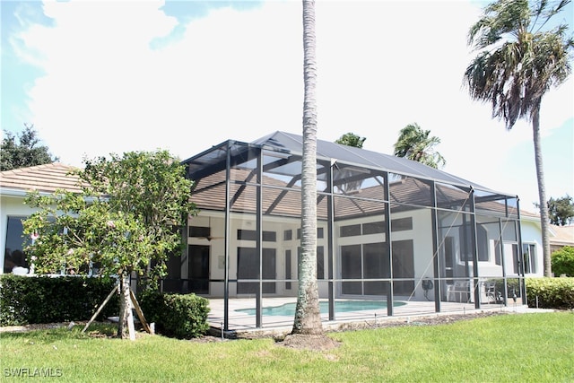 back of house featuring a lawn and glass enclosure