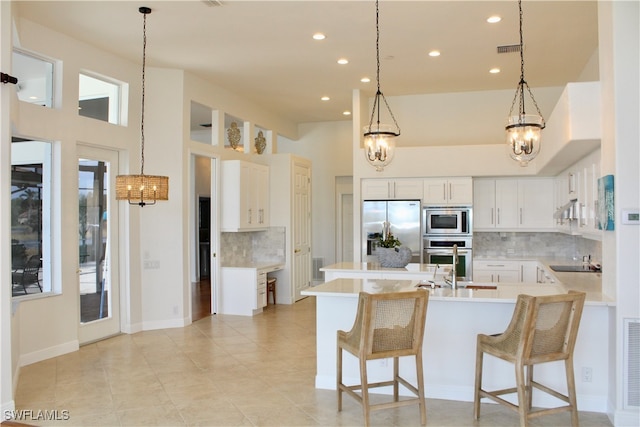 kitchen with light tile patterned floors, a breakfast bar area, decorative backsplash, white cabinets, and appliances with stainless steel finishes