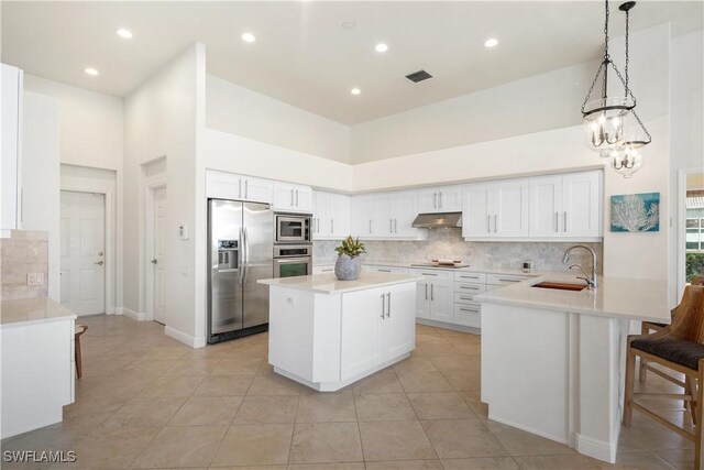 kitchen with tasteful backsplash, appliances with stainless steel finishes, a sink, a peninsula, and under cabinet range hood