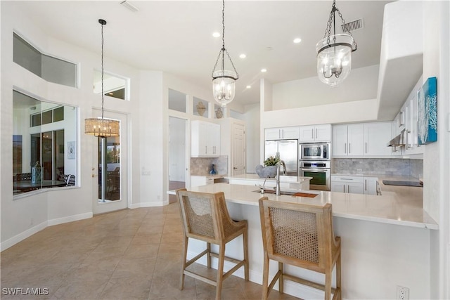 kitchen with an inviting chandelier, under cabinet range hood, appliances with stainless steel finishes, and a sink