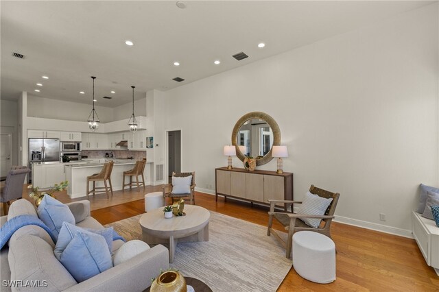 living area with baseboards, light wood-style flooring, visible vents, and recessed lighting