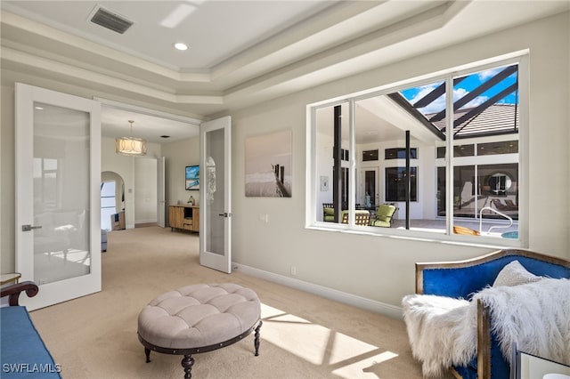 sitting room with carpet, visible vents, arched walkways, and french doors